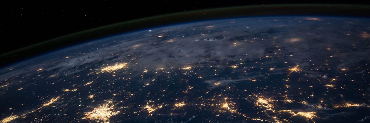 Nighttime view of Earth from space with glowing city lights.